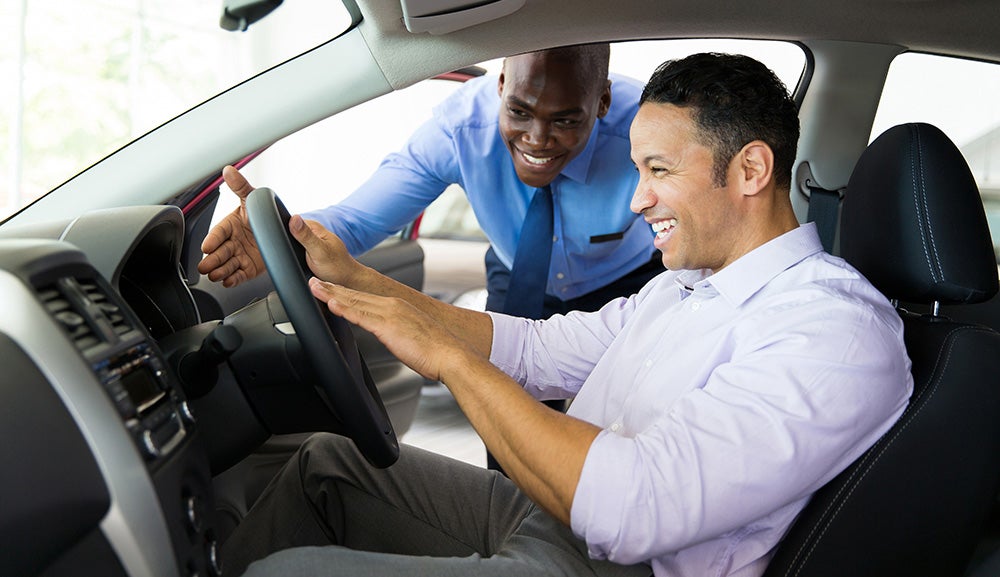 Salesperson showing a customer the features of a new car during a test drive